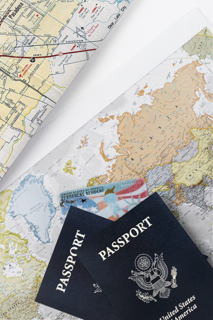 Two US passports and a Permanent Resident card (Green Card) laid on a world map and a local road map, symbolizing international travel and immigration.